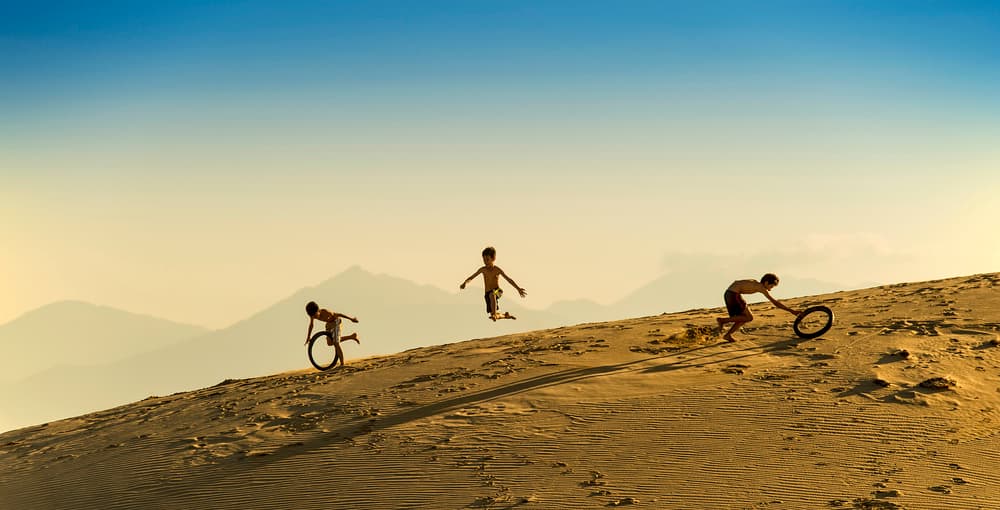 Kids Running Desert Dunes by Burak Senbak — canvas wall art