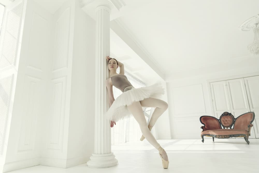 ballerina in a light bodysuit and tutu is standing in the room leaning on a pole by Alexandr — canvas wall art