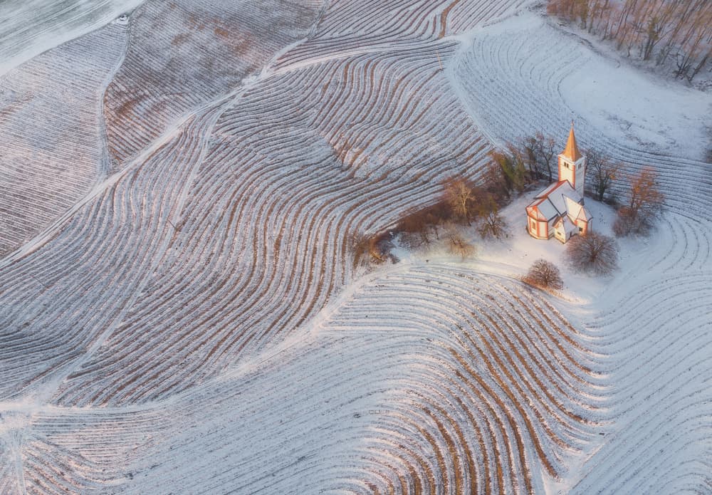 Winding Snowy Field Church by Ales Komovec — canvas wall art