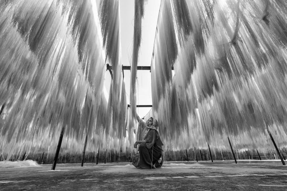Woman Amidst Drying Noodles by Azim Khan Ronnie — canvas wall art