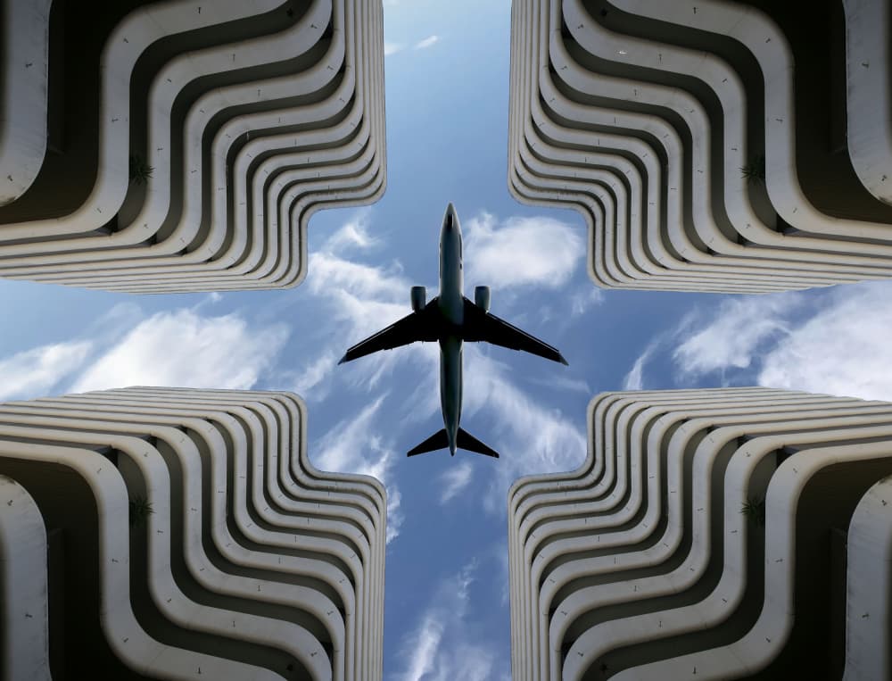 Airplane Over Urban Architecture by Yohan Borca — canvas wall art