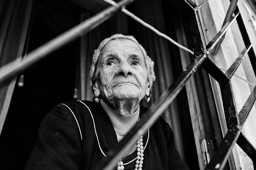 Elderly Woman Behind Bars by Josefina Melo — canvas wall art