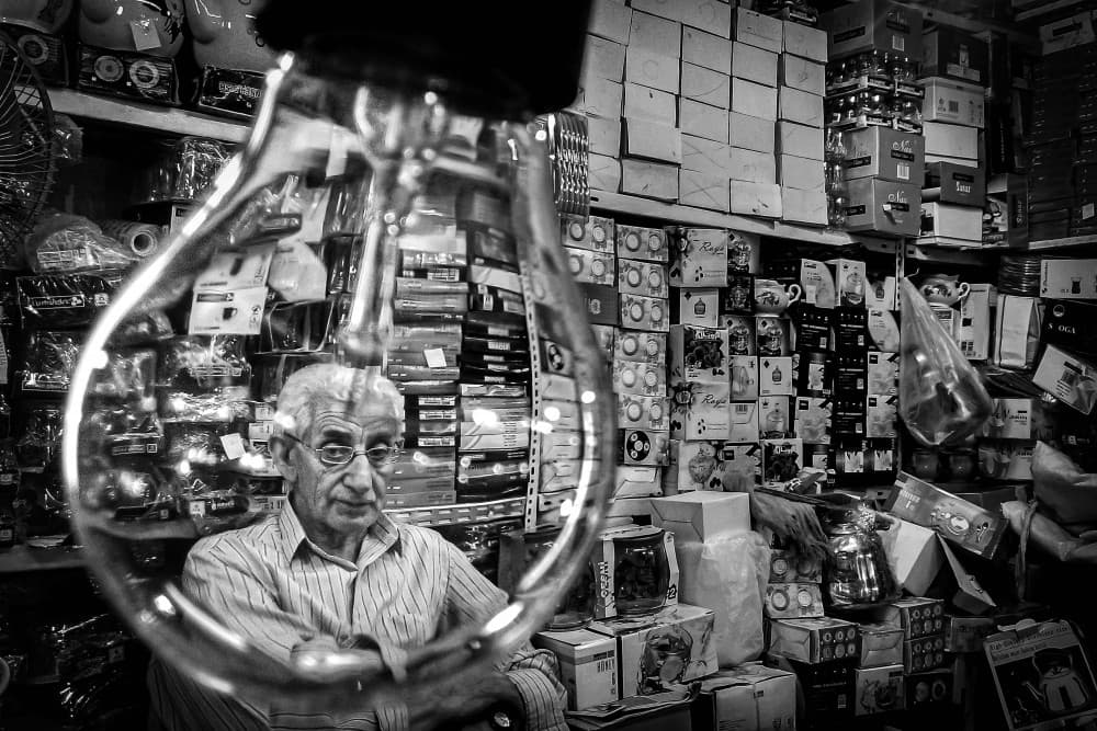 Shopkeeper Through Bulb by Shamal Shakibayi — canvas wall art