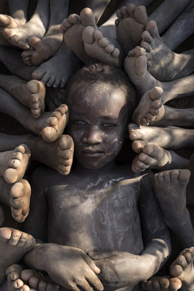 Child Surrounded By Feet by Sarawut Intarob — canvas wall art