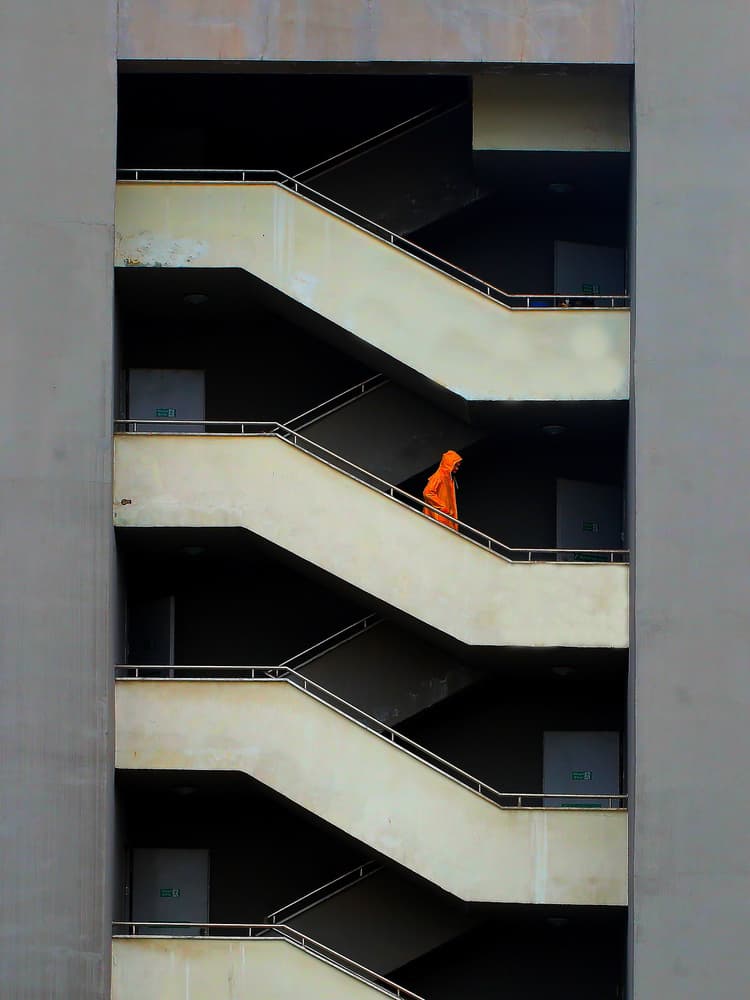 Orange Hooded Figure Stairs by Mustafa Binol — canvas wall art