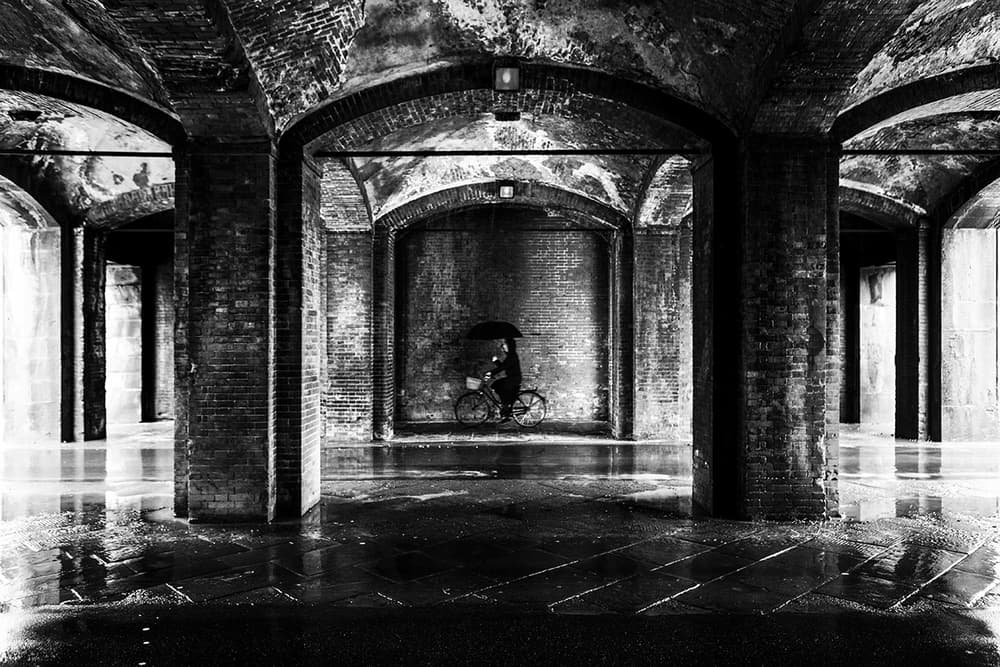 Cyclist Under Dark Arches by Massimo Della Latta — canvas wall art