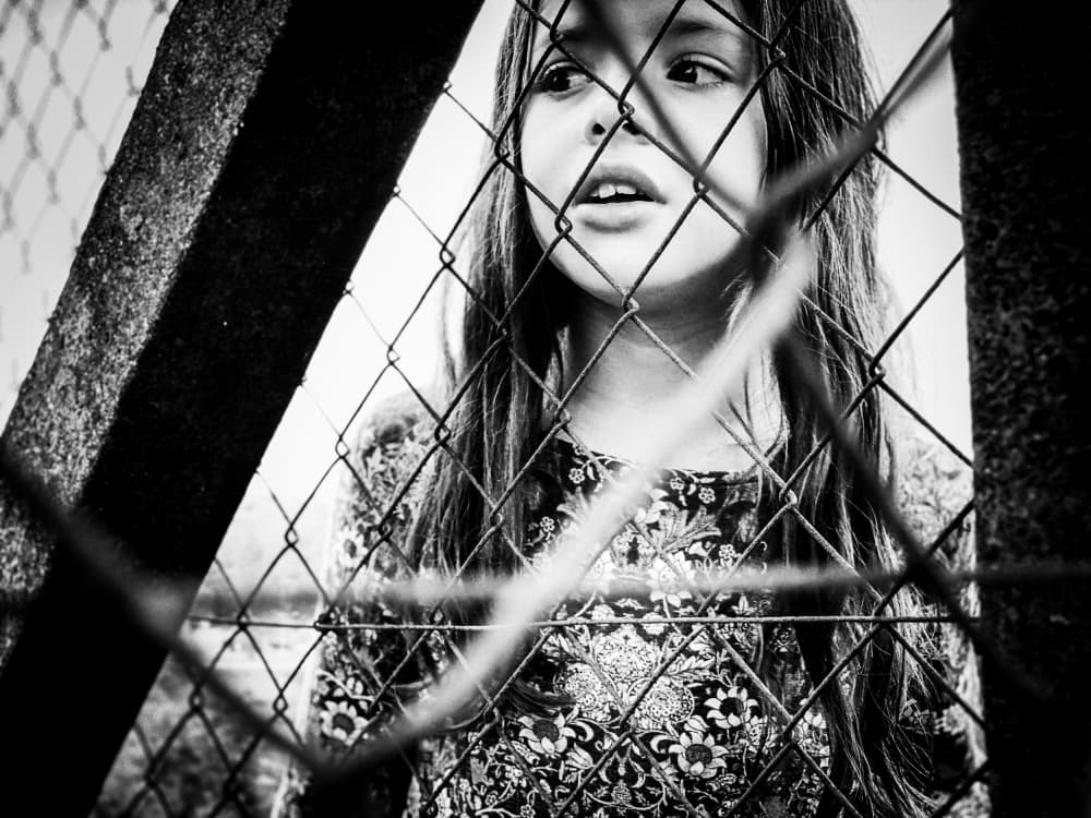 Curious Girl Behind Fence by Delphine Margau — canvas wall art