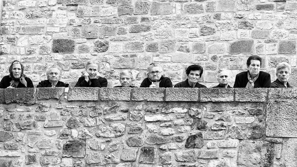 Watchful Faces Stone Wall by Walter Caterina — canvas wall art