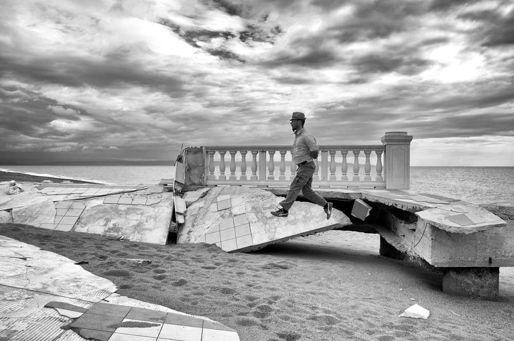 Man Strides Coastal Ruin by Carlo Ferrara — canvas wall art