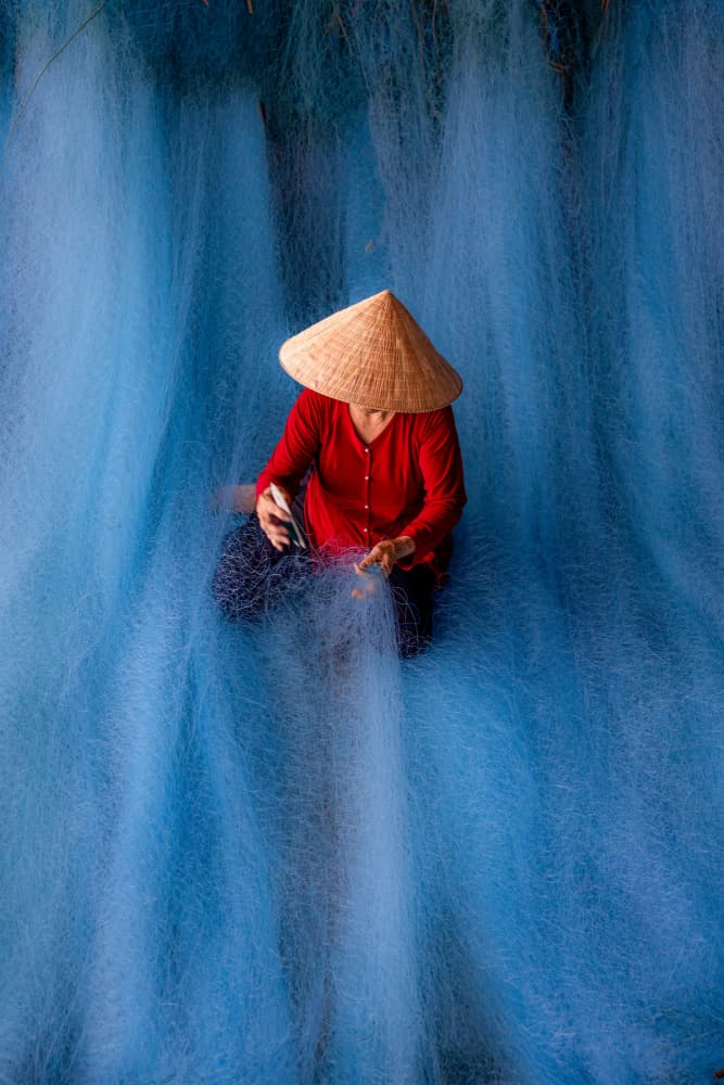 Woman Mending Blue Nets by Sally Widjaja — canvas wall art