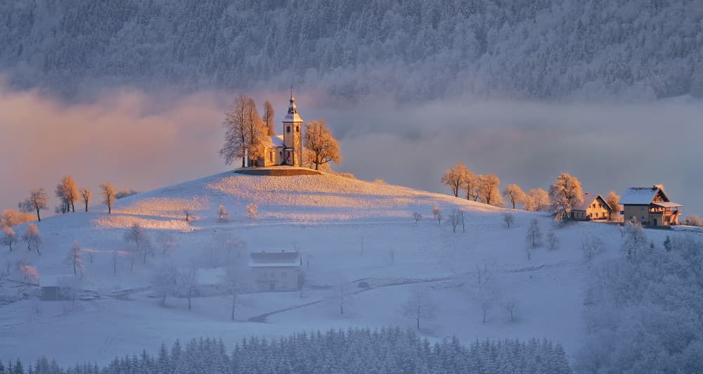 Snowy Hilltop Church Glow by Drago Vogrinec — canvas wall art