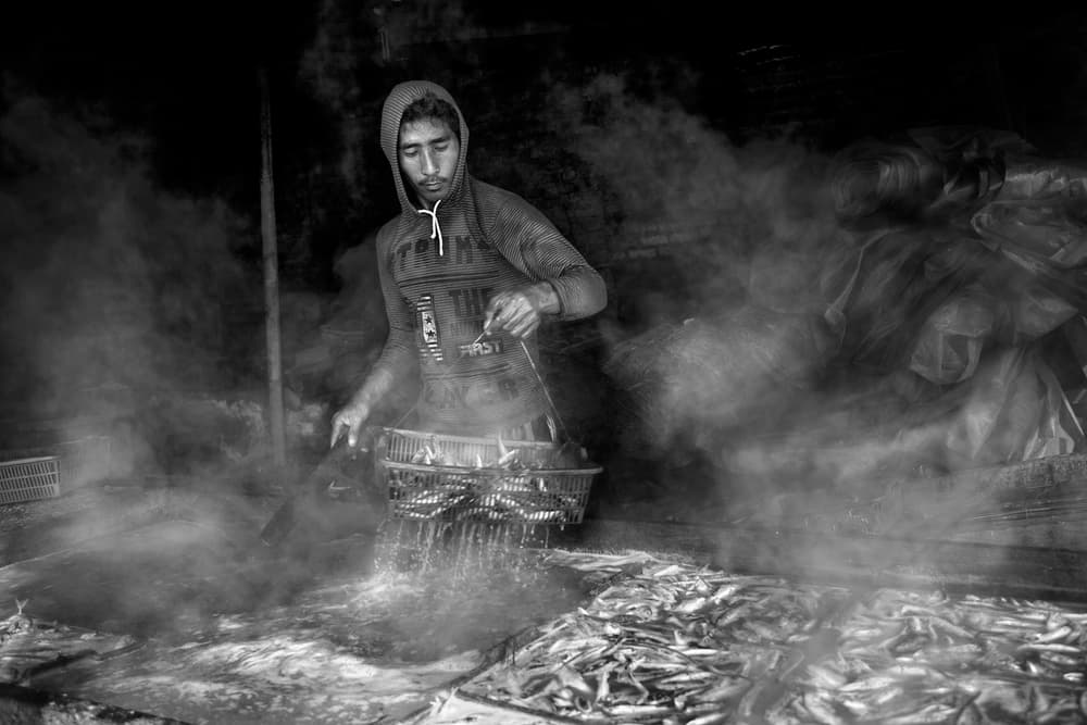 Man Prepares Steaming Fish by Hari Sulistiawan — canvas wall art