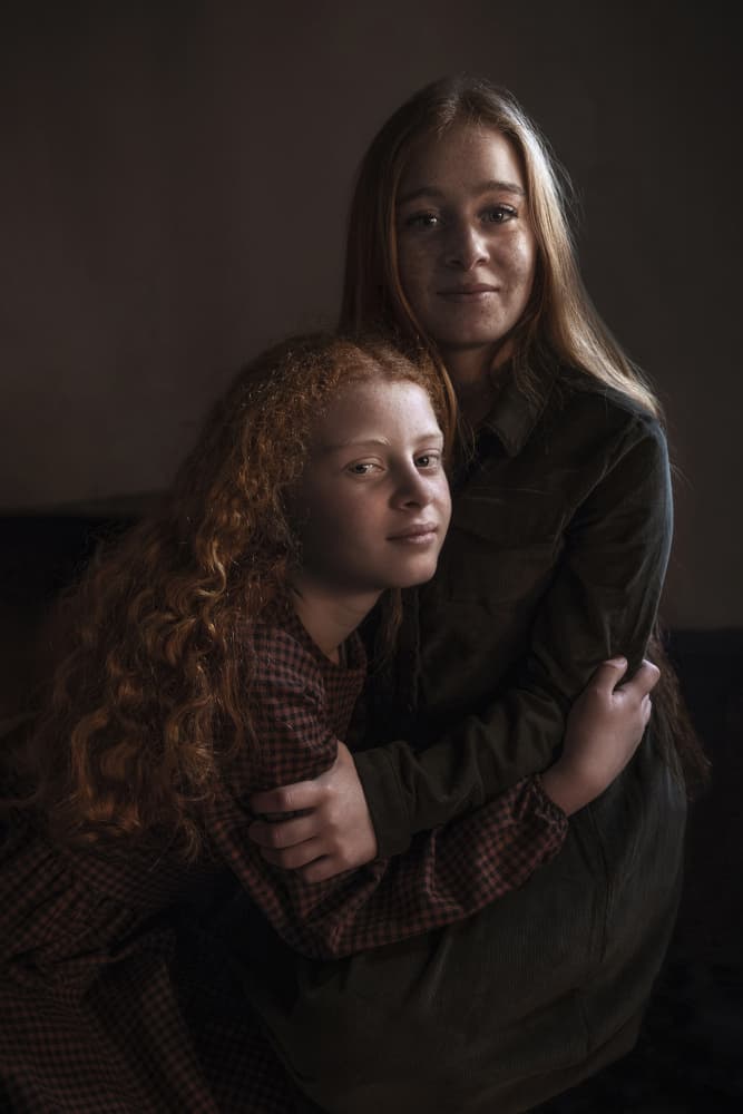Young Sisters Embrace by Emel Sefer — canvas wall art