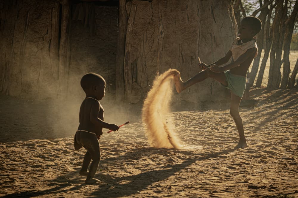 African Children Kicking Sand by Mei Shi — canvas wall art