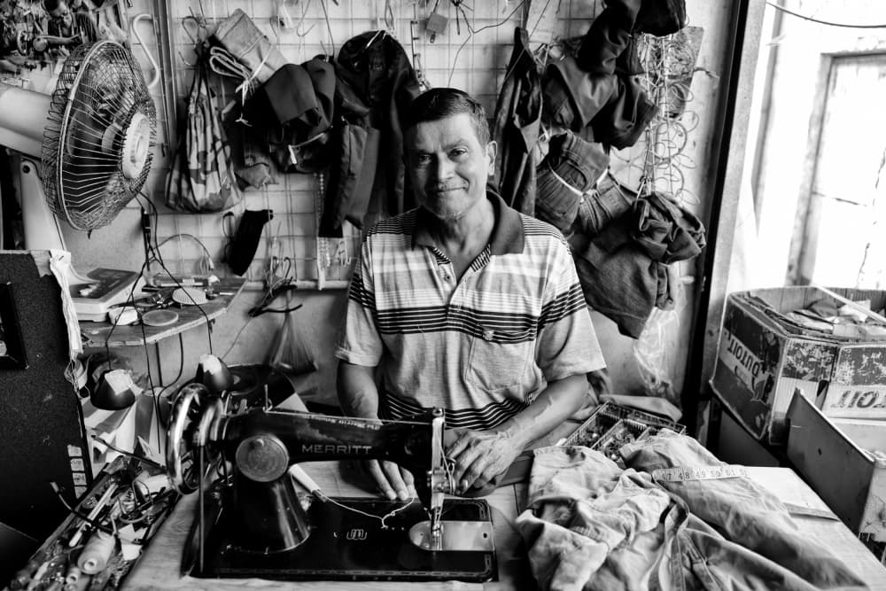 Smiling Tailor At Work by Kieron Long — canvas wall art