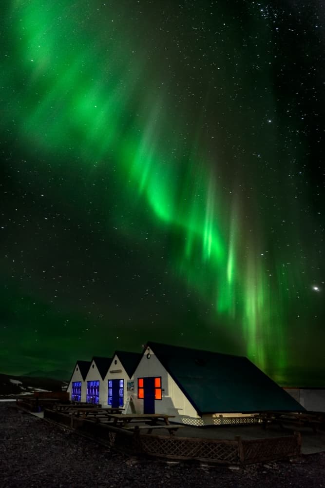 Vibrant Aurora Over Cabins by Jesús M. García — canvas wall art