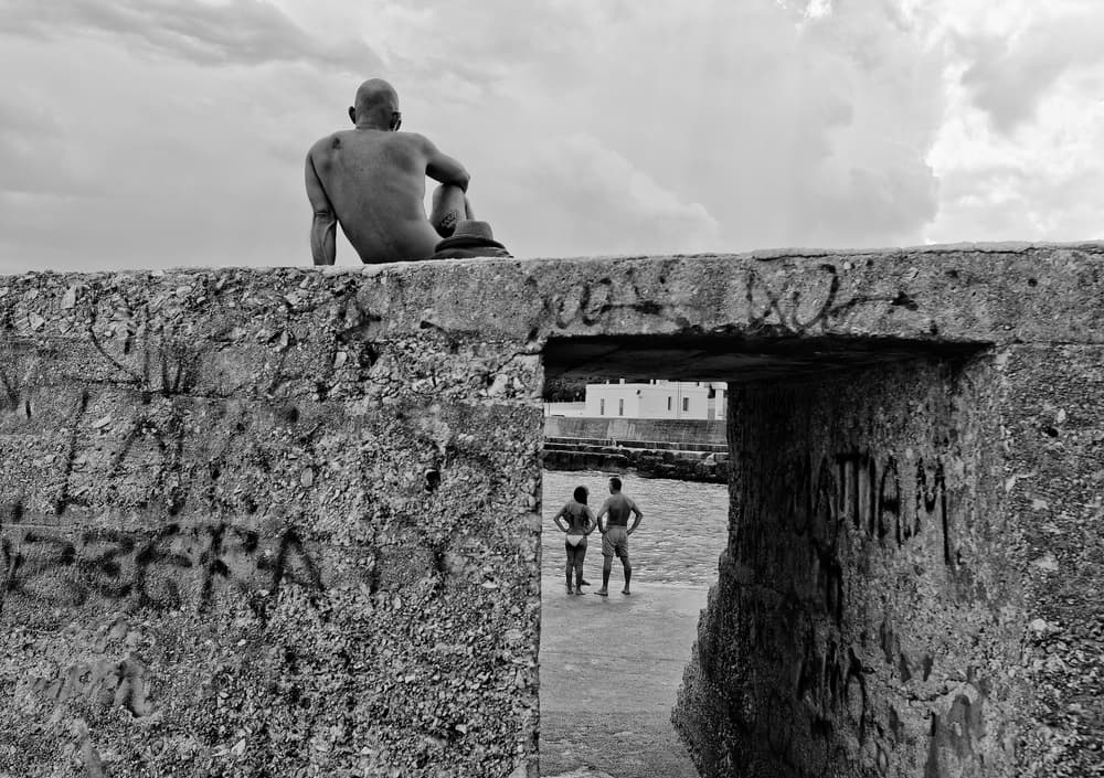 Man on Coastal Wall by Lorenzo Grifantini — canvas wall art