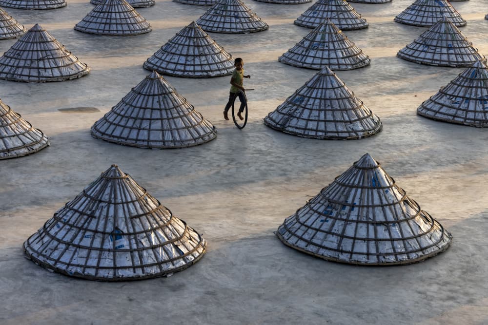 Boy with Unicycle in Salt Field by Azim Khan Ronnie — canvas wall art