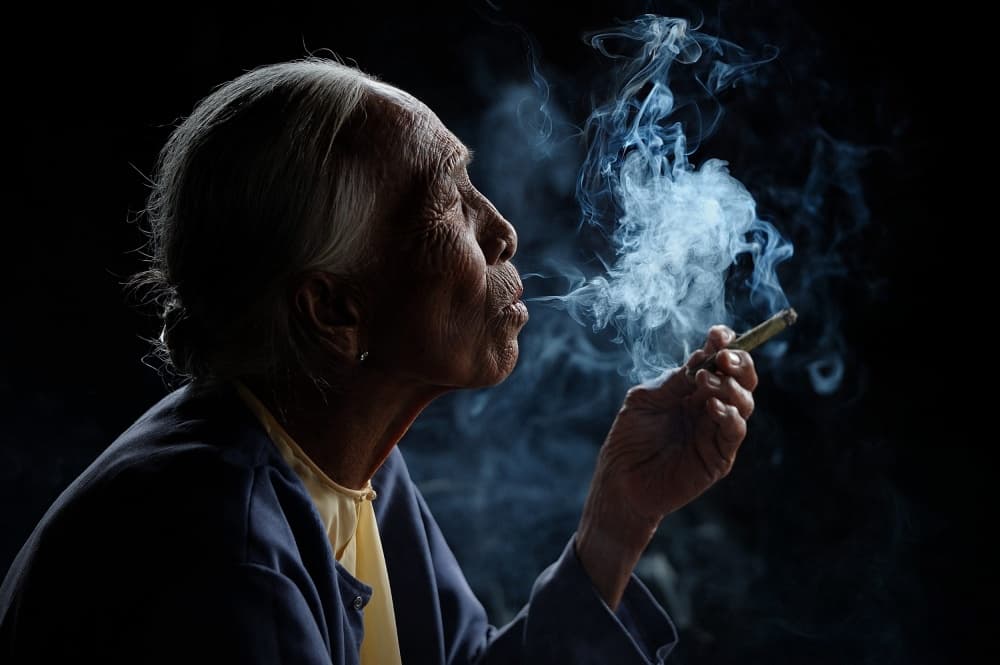 Elderly Woman's Quiet Smoke by Vichaya — canvas wall art
