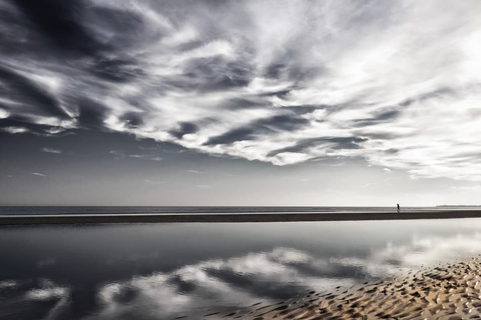 Lone Walker on Reflective Beach