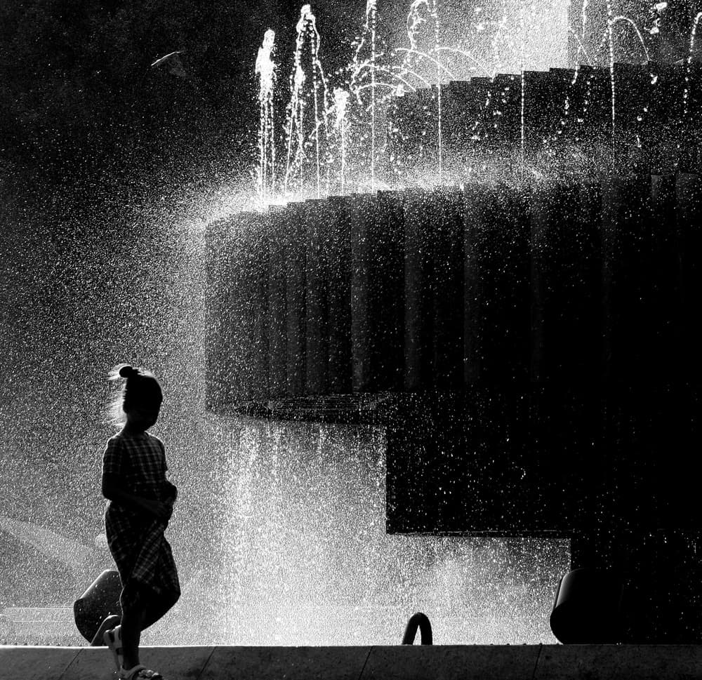 Child In Fountain Spray by Amihay Shraga — canvas wall art