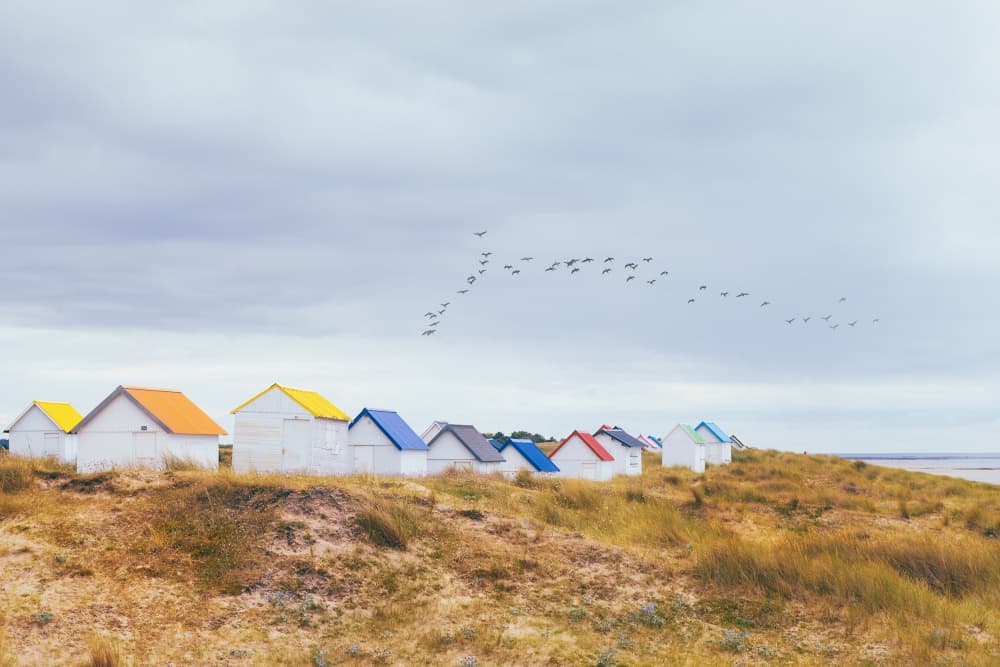 Colorful Coastal Huts Flight by Uschi Hermann — canvas wall art