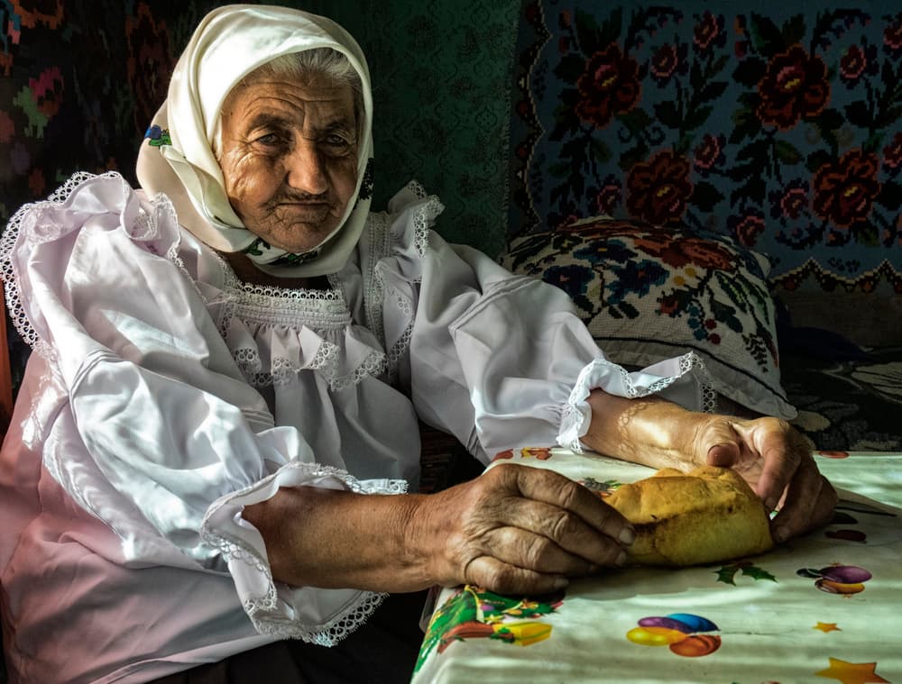 Old Woman Breaking Bread by Andrei Nicolas - The Traveler — canvas wall art