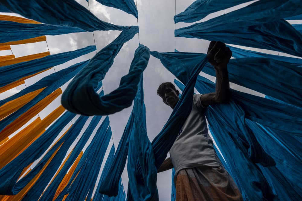 Man Hanging Colorful Fabrics by Azim Khan Ronnie — canvas wall art