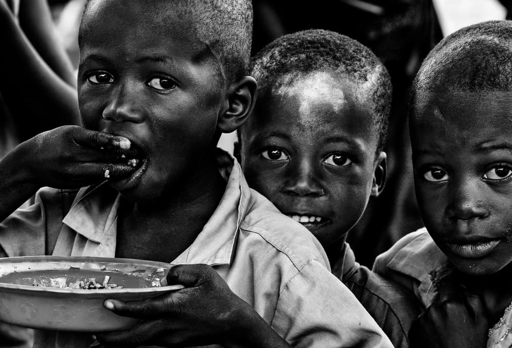 African Children Sharing Meal by Joxe Inazio Kuesta Garmendia — canvas wall art