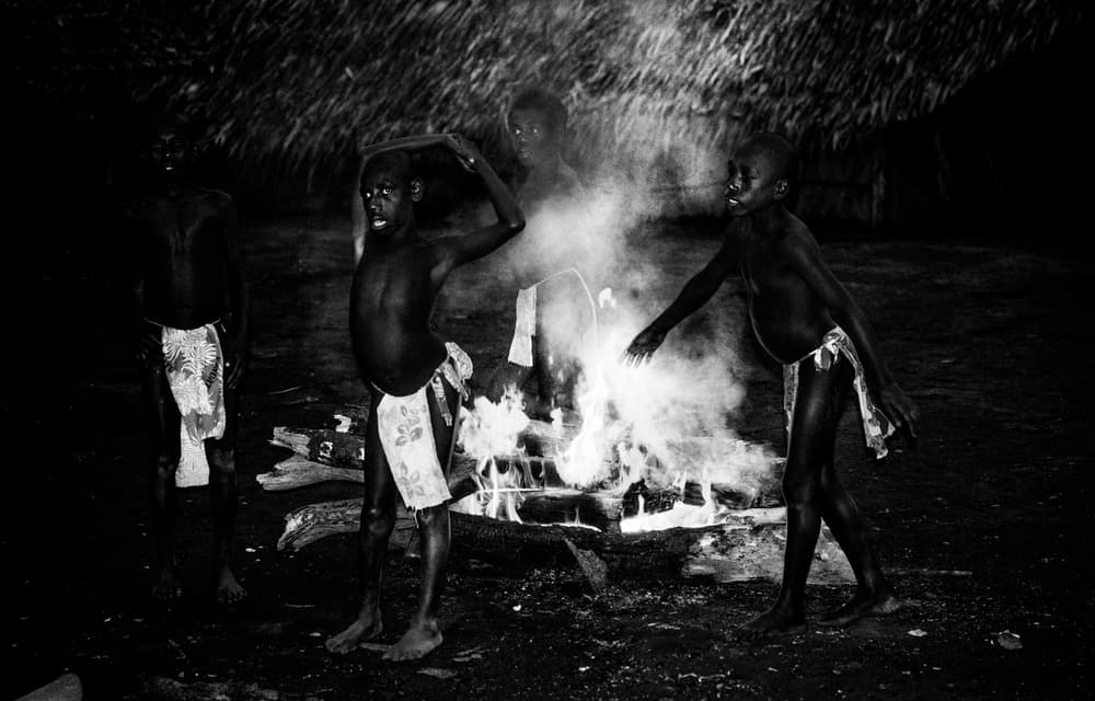African Boys Firelight by Joxe Inazio Kuesta Garmendia — canvas wall art