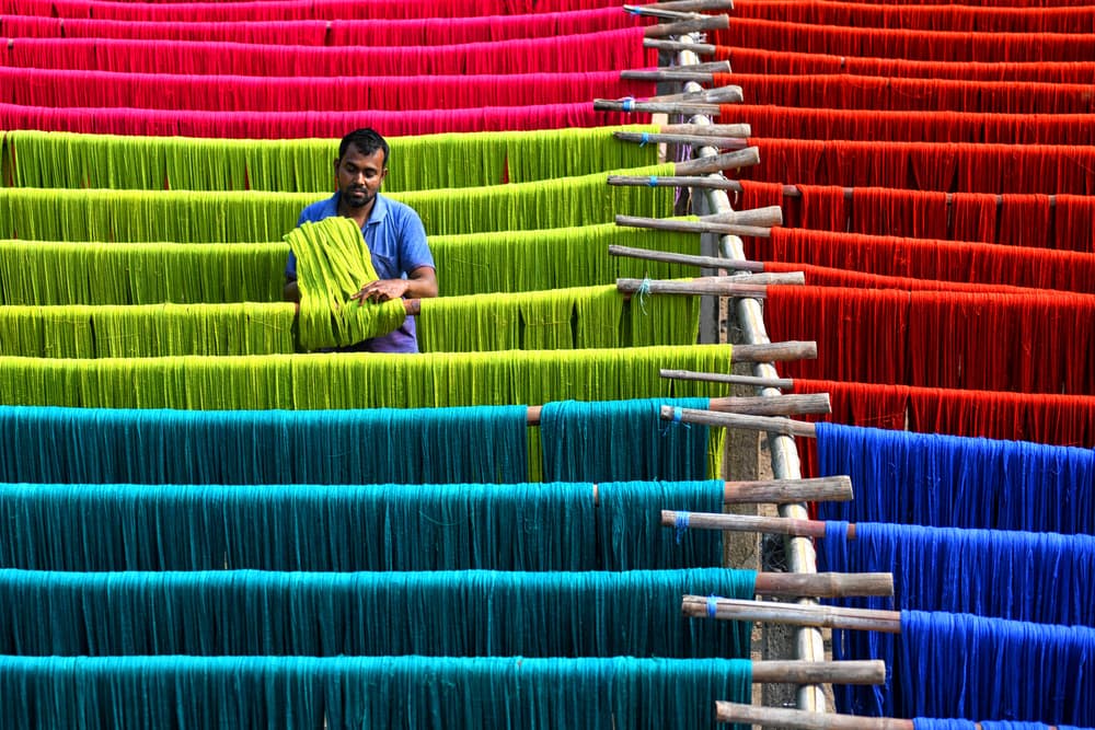 Man Drying Colorful Textiles by Avishek Das — canvas wall art