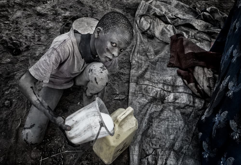 Mundari child passing the freshly milked milk to another container. by Joxe Inazio Kuesta Garmendia — canvas wall art