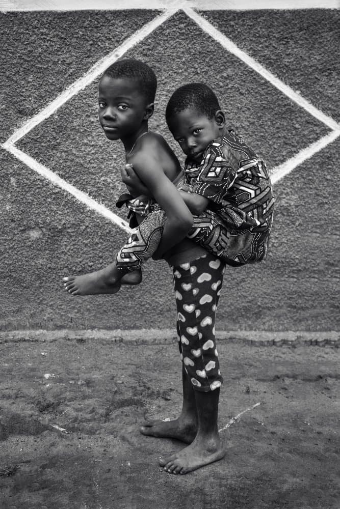 African Boys Piggyback Ride by Emel Sefer — canvas wall art