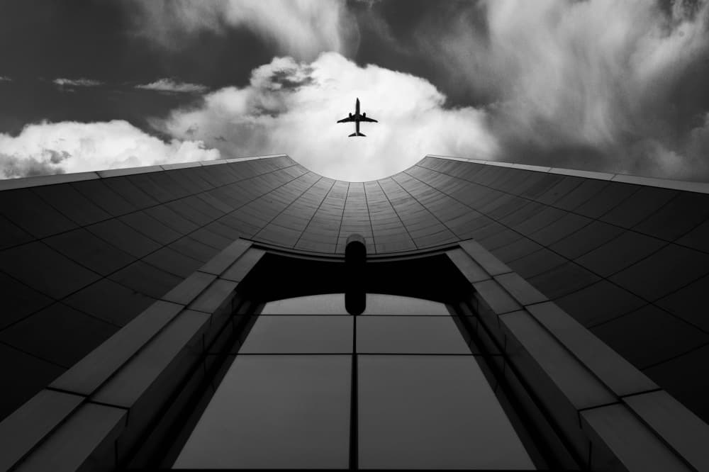Plane Over City Building by Jorge Pimenta — canvas wall art
