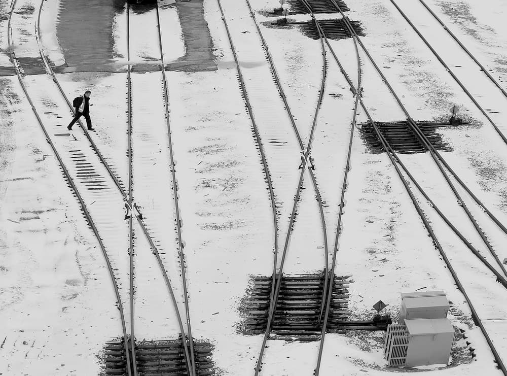 A Man Walks Along Snowy Train Tracks by Jian Wang — canvas wall art
