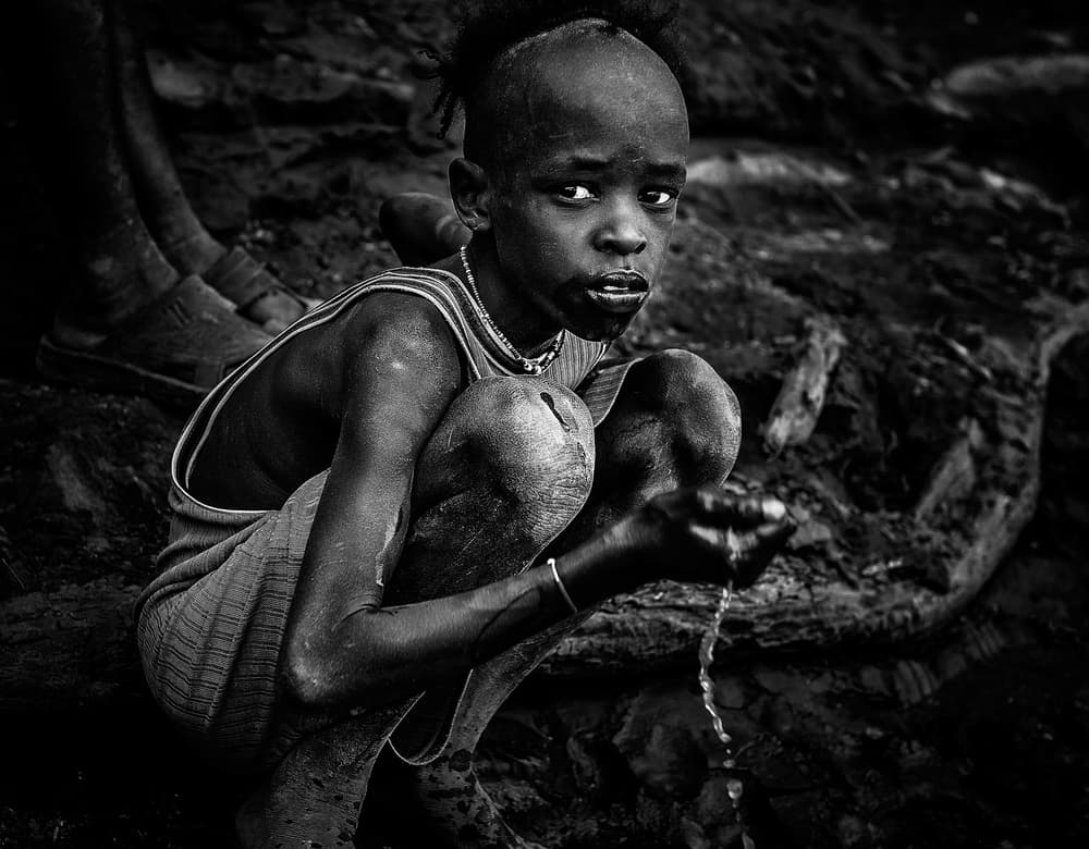 African Boy Drinking Water by Joxe Inazio Kuesta Garmendia — canvas wall art