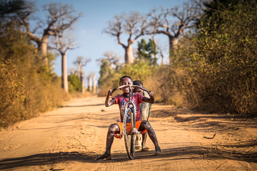 African Boy's Playful Ride by Marco Tagliarino — canvas wall art