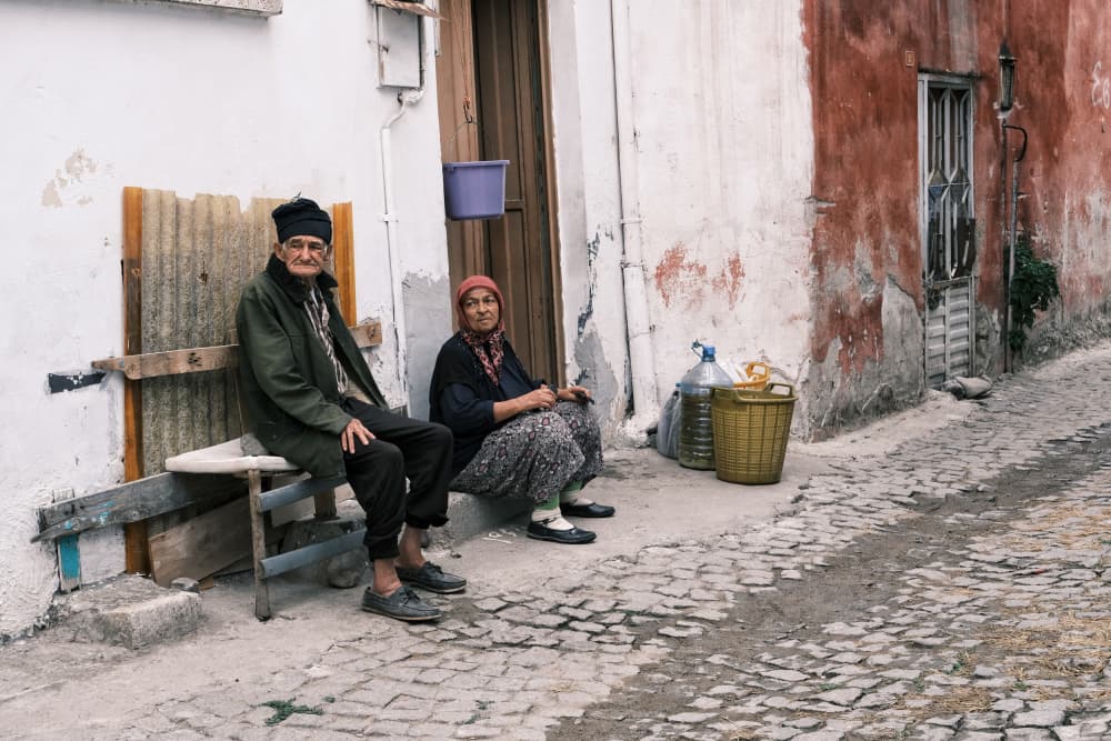 Elderly Couple Village Street by Ali Ayer — canvas wall art