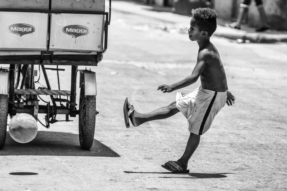 Boy Kicking Street Ball by Pavol Stranak — canvas wall art