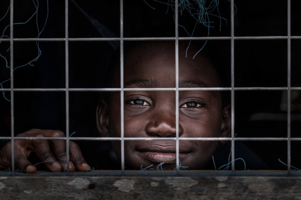 Smiling Child Behind Bars by Joxe Inazio Kuesta Garmendia — canvas wall art