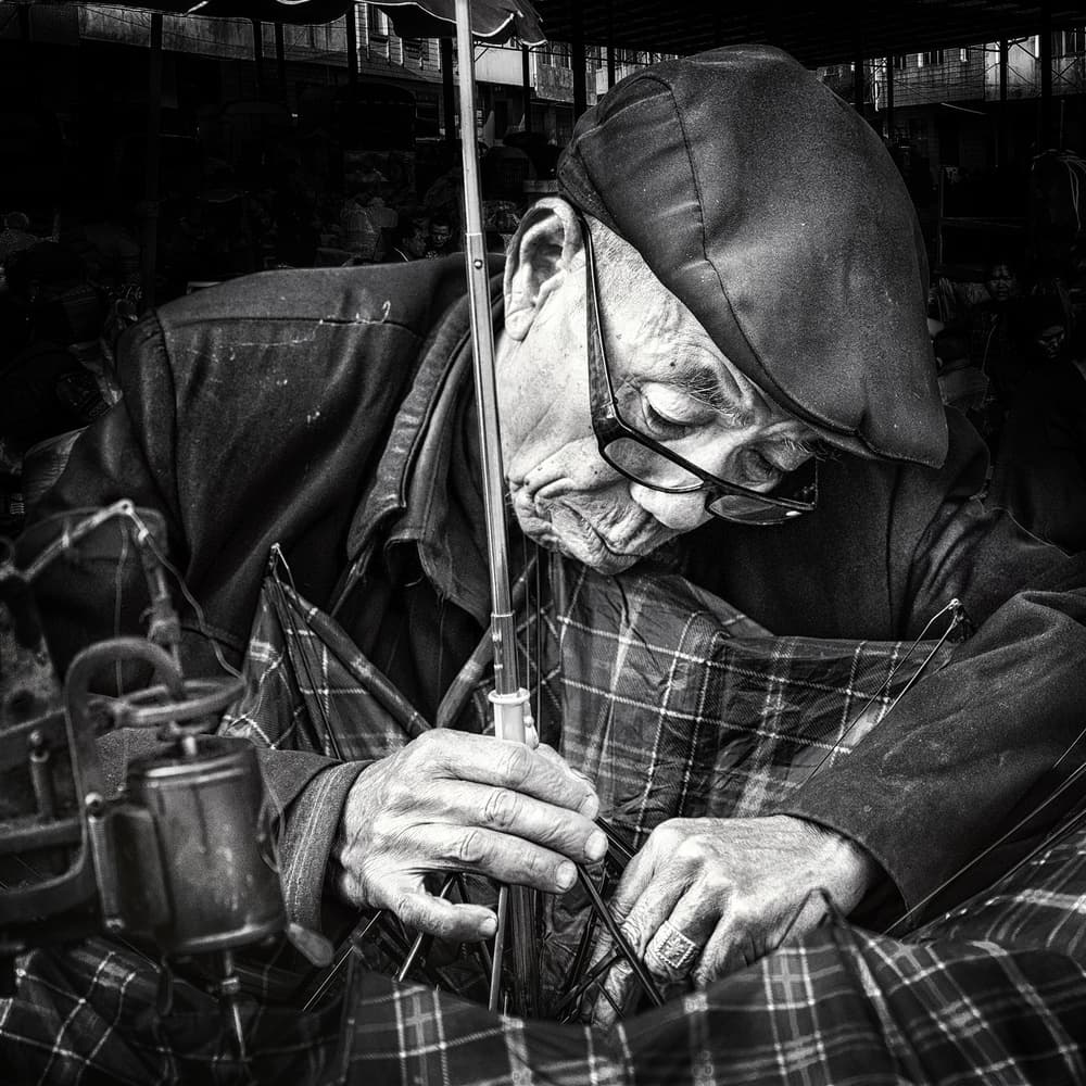 Focused Umbrella Repairman by Piet Flour — canvas wall art