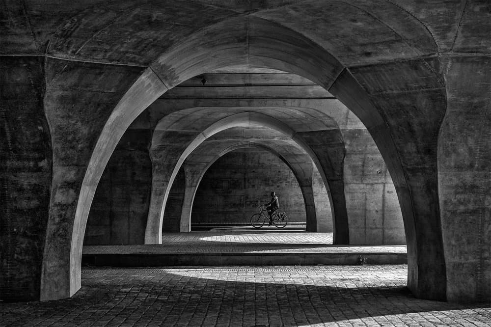 Cyclist Under Arches by Jef Van den Houte — canvas wall art