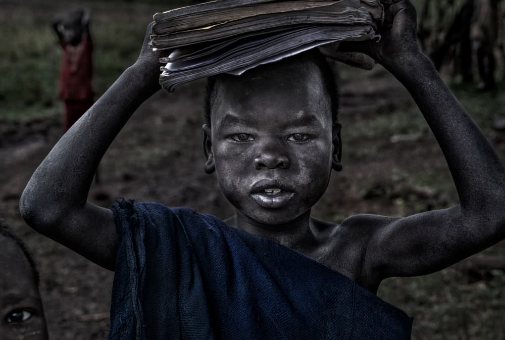 African Child With Books by Joxe Inazio Kuesta Garmendia — canvas wall art
