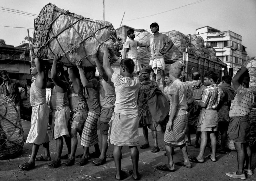 Men Carrying Heavy Bundles by Avishek Das — canvas wall art
