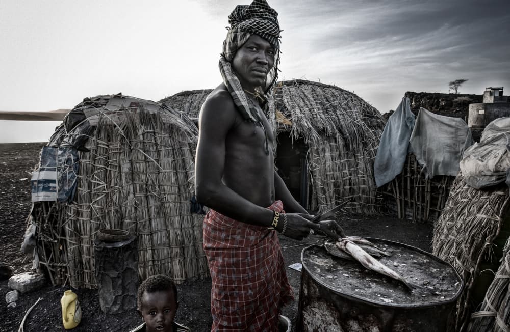 African Man Prepares Fish by Joxe Inazio Kuesta Garmendia — canvas wall art