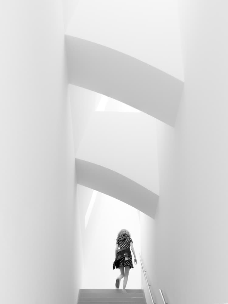 Woman Ascending Bright Stairwell by Andy Bauer — canvas wall art