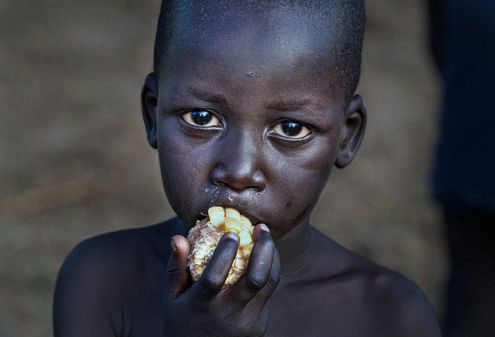 African Child Eating Corn by Joxe Inazio Kuesta Garmendia — canvas wall art