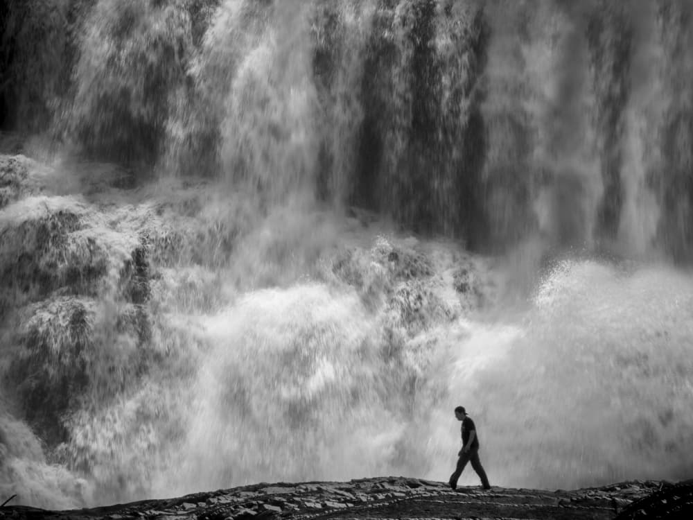 Man and Rushing Waterfall by David Senechal Photographie (polydactyle) — canvas wall art