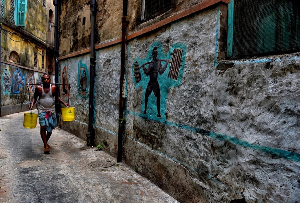 Man Carrying Buckets Mural by Avishek Das — canvas wall art